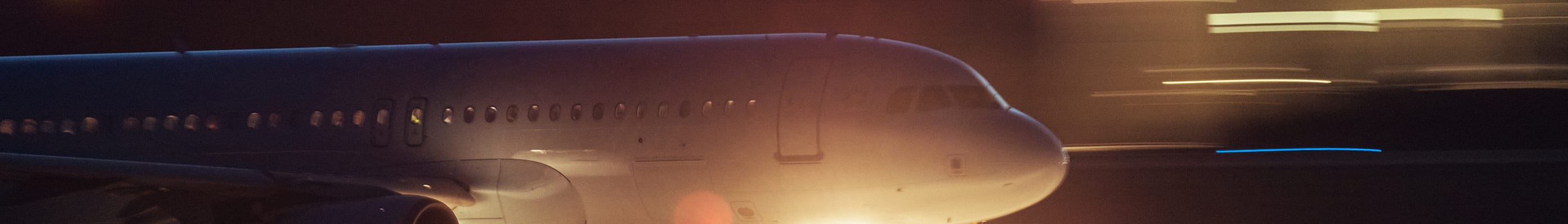 Image of passenger jet moving from left to right, with lights zooming past.